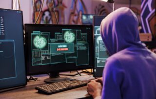 A hacker in front of a computer screen that displays "Access denied"